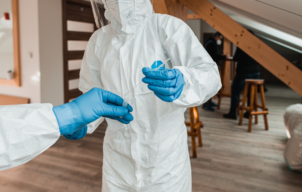 Technician in protective gear performing mold testing.
