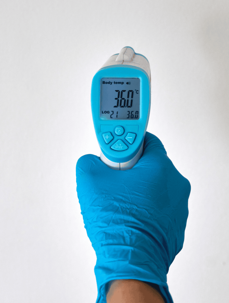 A hand holding a digital thermometer displaying body temperature.